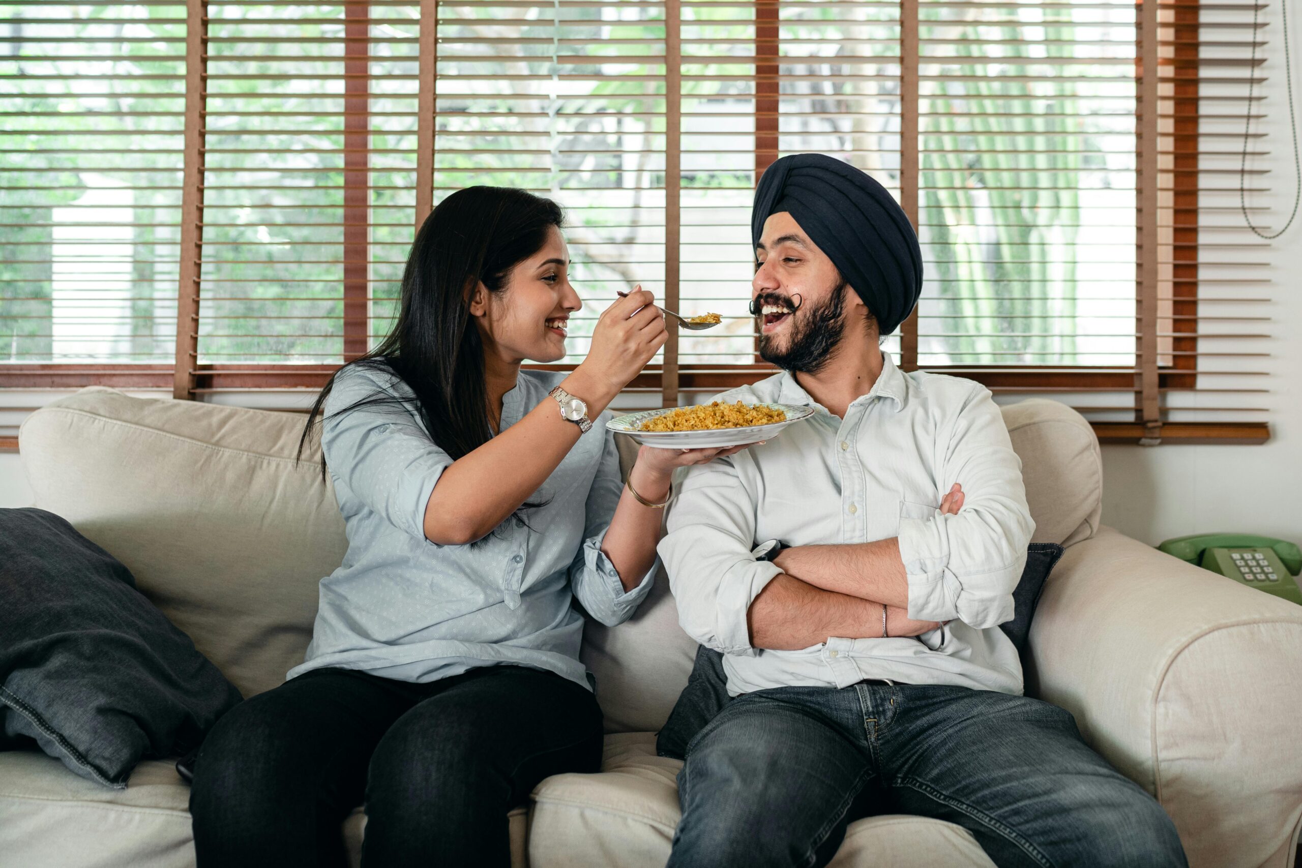 Couple sharing food on their sofa