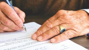 Older hands filling out and signing a document